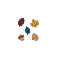 Five autumn-themed enamel pins on a plain white background: two leaves, one acorn, and one pine cone. The leaves and acorn are in dark red and teal, while the pine cone and acorn caps are tan and brown.