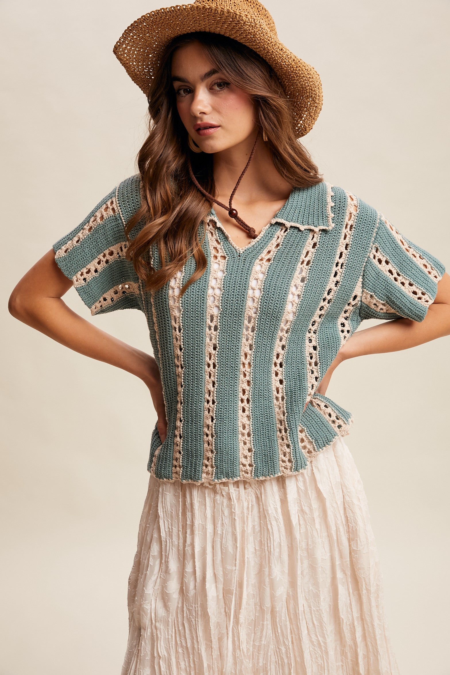 Woman wearing a crochet top and straw hat on a beige background