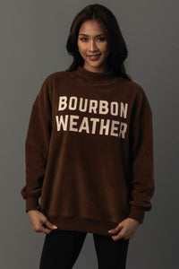 Woman wearing a brown sweatshirt with 'Bourbon Weather' text on a gray background