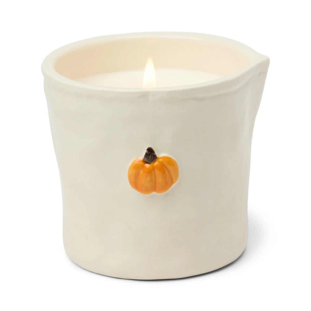 A lit cream-colored ceramic candle holder with a small orange pumpkin decoration on the front, set against a plain white background.