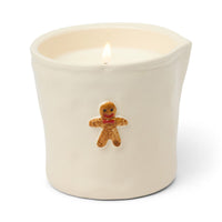 Candle in a white container with a gingerbread man decoration on a white background