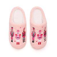 A pair of fuzzy light pink slip-on slippers decorated with colorful nutcracker soldier illustrations, shown against a plain white background.