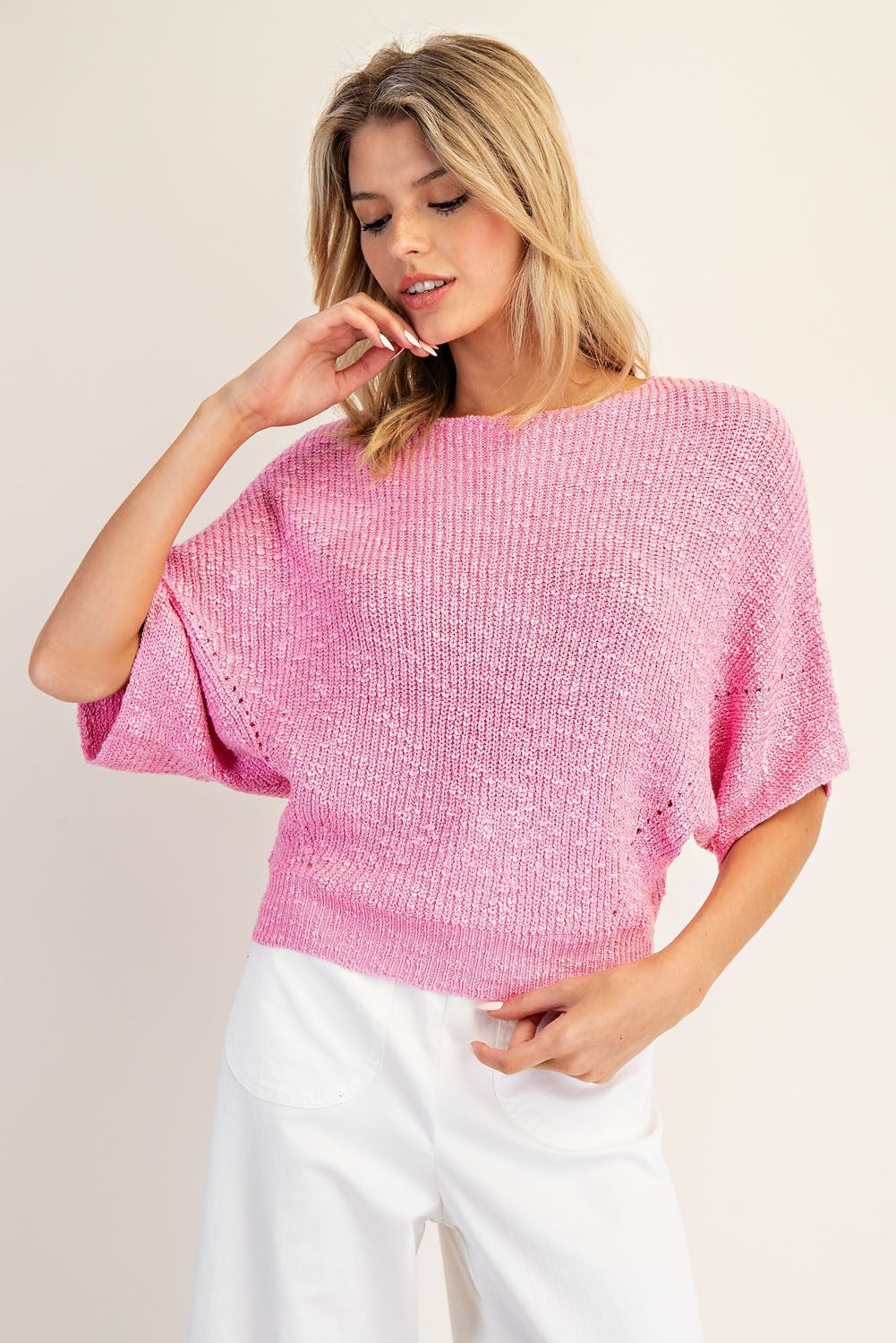 Woman wearing a pink knitted top against a plain background