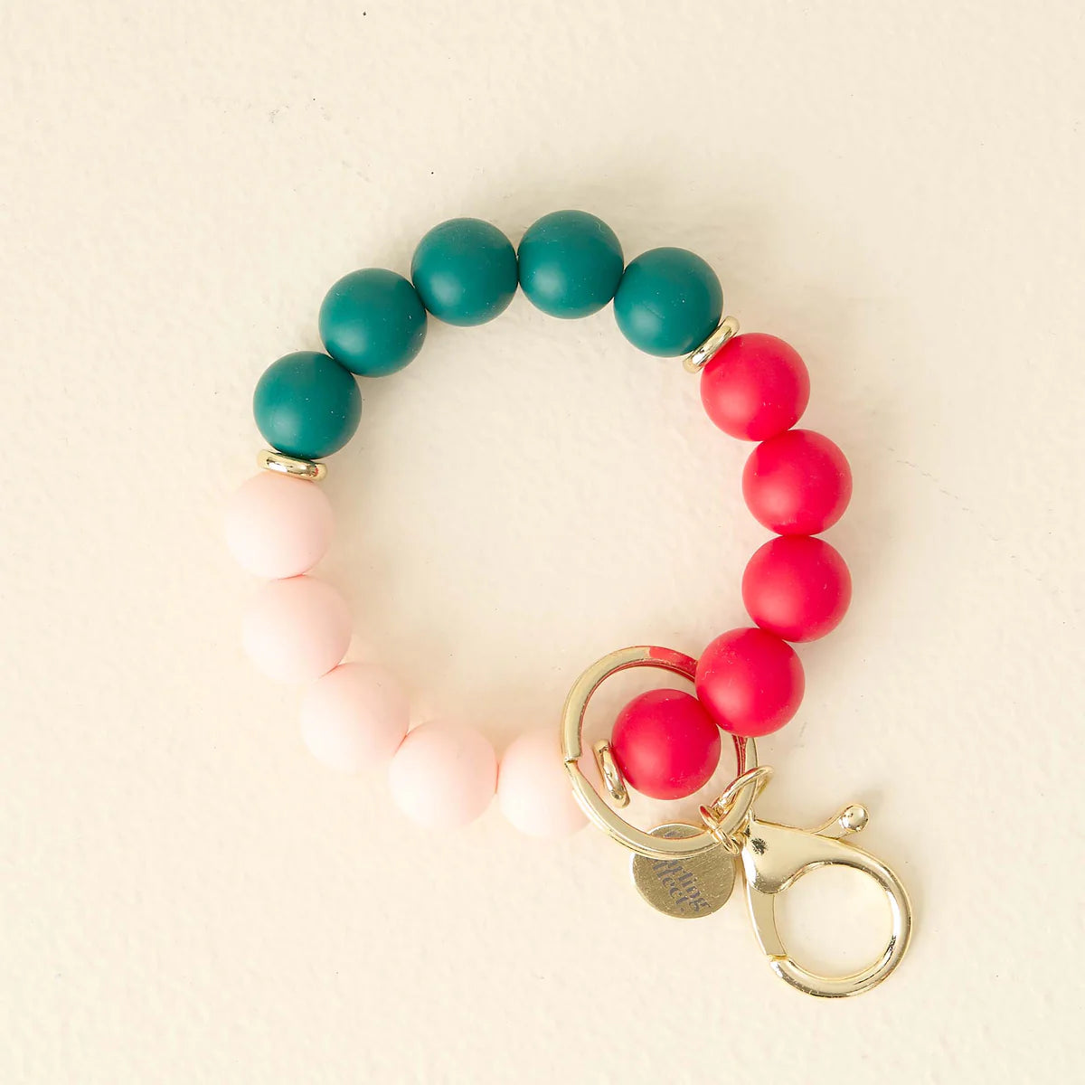 Beaded bracelet with pink, red, and green beads on a beige background