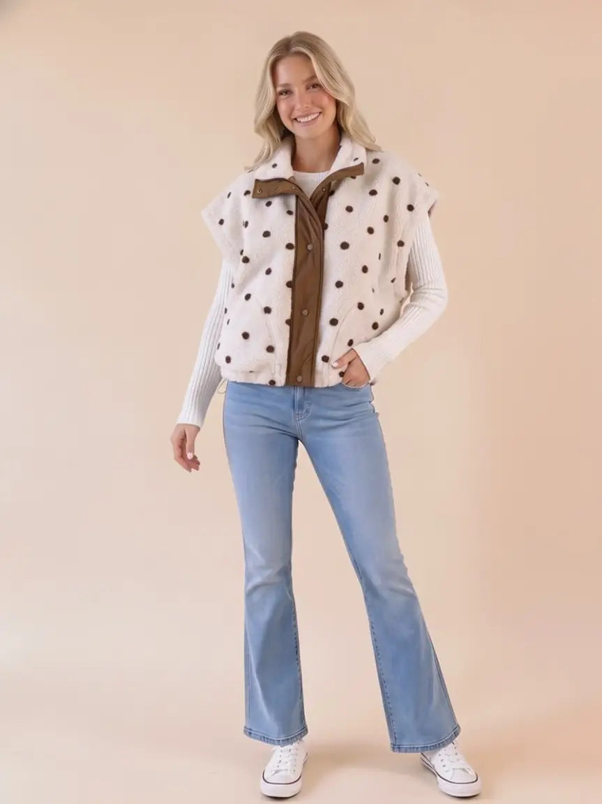 he Polkadot Sherpa Vest from Star Drop is a contemporary take on a preppy outerwear piece for women.

With its charming polka dot design, this vest is perfect for everyday wear during the fall and winter seasons. The short sleeve cut adds a unique twist, while the ribbon detail brings a hint of sophistication. This vest, inspired by individuality and adventure, moves with you, ensuring style, comfort, and confidence wherever life takes you. It's thoughtfully crafted in small batches, embodying Star Drop's c